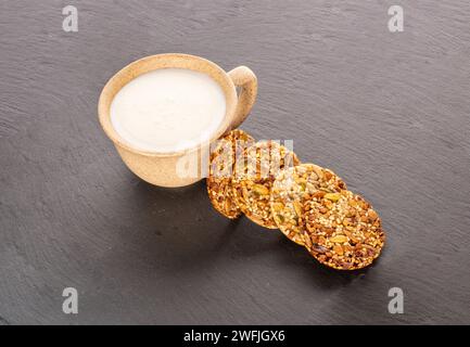 Ein paar Thaler-Kekse auf einem Schieferstein mit einer Tasse Sauerrahm, Nahaufnahme. Stockfoto