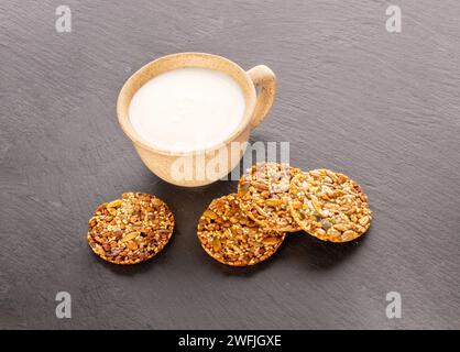 Ein paar Thaler-Kekse auf einem Schieferstein mit einer Tasse Sauerrahm, Nahaufnahme. Stockfoto