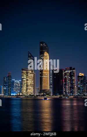 Die Skyline von Abu Dhabi in der Nacht mit einem Boot, das entfernt ist - Abu Dhabi, VAE Stockfoto