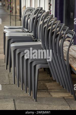 An sonnigen Tagen stehen neben der Terrasse des Cafés stapelbare silbergraue Plastikstühle. Detaillierte Darstellung von Musterstapel Kunststoffstühle, Platz für Text, Sel Stockfoto