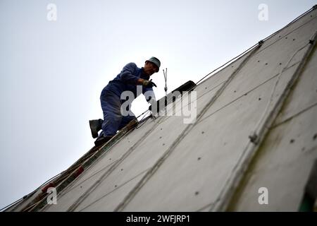 Der Dachdecker klettert die Leiter hinauf zum Dach Des Hauses, um Blechdach zu befestigen Stockfoto