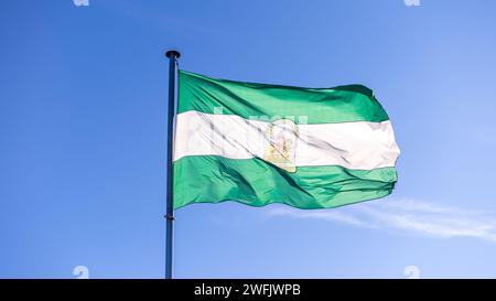 Die aktuelle Flagge Andalusiens winkt im Wind mit blauem Himmel. Andalusisches Banner, weicher und glatter Seide. Textur aus Stoff, Hintergrund. U Stockfoto