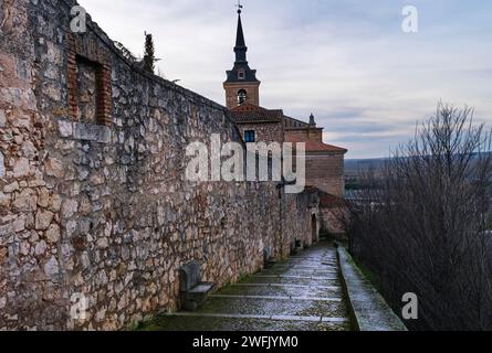 Blick auf das Äußere der Stadtmauer von Lerma, mit einem Kirchturm im Hintergrund. Stockfoto