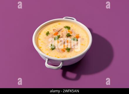 Köstliche griechische Hühnersuppe mit Zitronensaft und Gemüse, in einer Schüssel aus weißer Emaille, isoliert auf einem farbigen Hintergrund Stockfoto