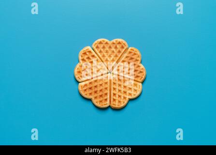 Blick von oben mit herzförmigen Waffeln, minimalistisch auf blauem Hintergrund Stockfoto