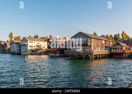 Historische Holzgebäude auf Pfählen ragen in der Penn Cove in Coupeville, Whidbey Island, Washington, ins Wasser. Stockfoto