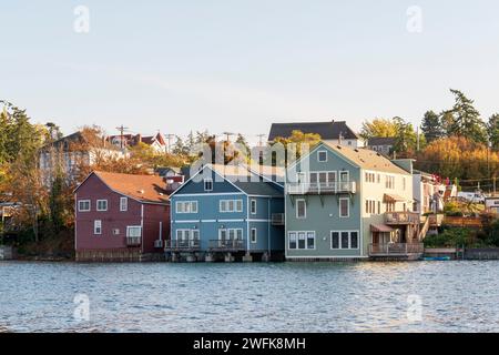 Farbenfrohe historische Holzgebäude auf Pfählen ragen in der Penn Cove in Coupeville, Whidbey Island, Washington, ins Wasser. Stockfoto