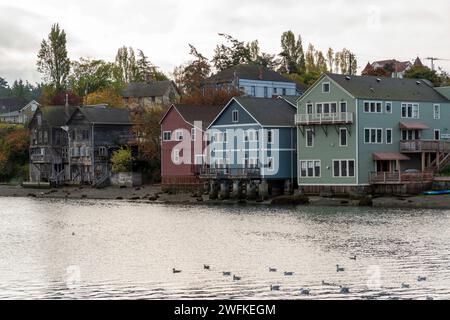 Farbenfrohe historische Holzgebäude auf Pfählen ragen in der Penn Cove in Coupeville, Whidbey Island, Washington, ins Wasser. Stockfoto