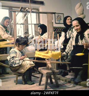 Vrancea County, Rumänien, ca. 1978. Gruppe von Frauen in wunderschönen traditionellen Kostümen, die Wolle spinnen, weben und nähen. Stockfoto