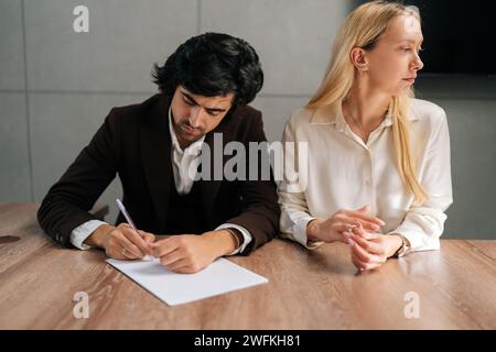 Porträt von traurigen Ehepaaren, die Dekrete unterzeichnen und sich im Büro der Anwälte am Schreibtisch scheiden lassen. Unglückliche Trennung der verheirateten Familie Ende Stockfoto