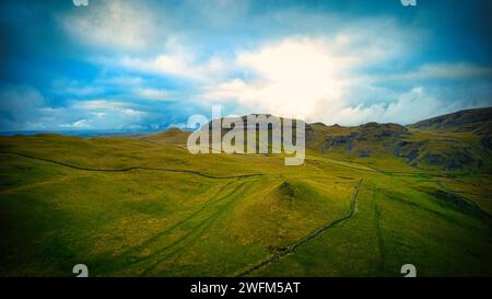 Malerische Landschaft mit üppigen grünen Feldern unter einem dramatischen Himmel mit Sonnenstrahlen, die durch Wolken ragen. Stockfoto