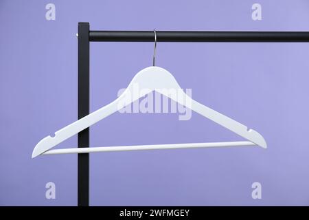 Weißer Kleiderbügel auf dem Regal vor violettem Hintergrund Stockfoto