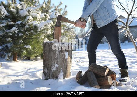 Mann hackt Holz mit Axt draußen am Wintertag, Nahaufnahme Stockfoto