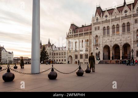 Kossuth Lajos Square bei Sonnenuntergang. Riesiger Fahnenmast mit ungarischer Flagge und ungarischem Parlamentsgebäude im Hintergrund. Sonnenuntergangsbeleuchtung in warmen Tönen. Stockfoto