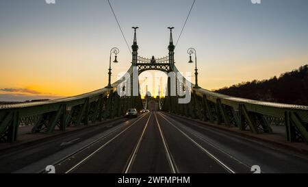 Liberty Bridge in der Abenddämmerung - symmetrische Ansicht. Blick vom Platz Fővám tér an der Brücke und am rechten Ufer der Donau. Weitwinkelsymmetrische Aufnahme der Brückenstruktur Stockfoto