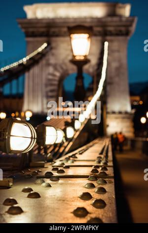 Selective focus photo of Széchenyi Chain Bridge at night. close-up view of rivets and lamps on chain bridge in Budapest. Stockfoto