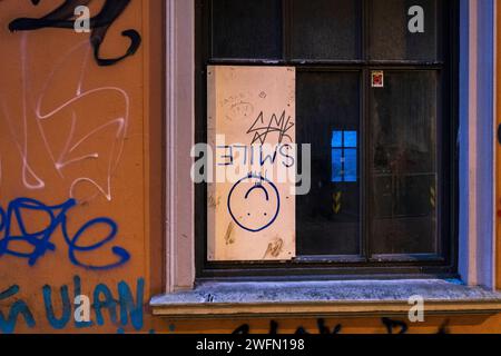 "Lächeln", lächelndes Gesicht auf einem Holzbrett in einer kaputten Glasscheibe Stockfoto