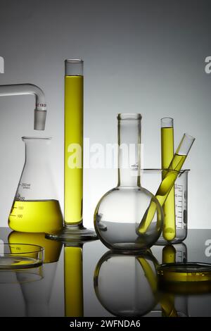 Laborglasgeräte mit gelber Flüssigkeit und Hintergrundbeleuchtung. Wissenschaftslaborforschungskonzept. Stockfoto