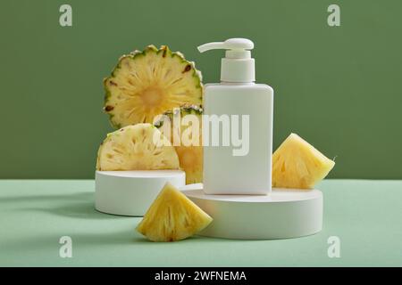 Weißes rundes Podium mit leerer Etikettenflasche und einigen Ananasscheiben auf grünem Hintergrund. Konzept des beruhigenden Naturschönheitsproduktextrakts Stockfoto