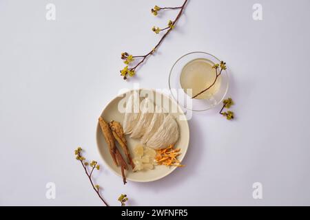 Ein Gericht mit essbarem Vogelnest mit Kräutern, Ginseng, Cordyceps, Steinzucker und Vogelnestsuppe in einem Glasbecher. Vogelnest kann Augenhöhen fördern Stockfoto