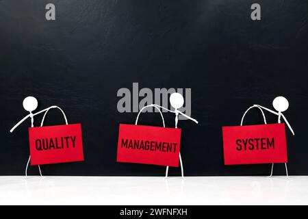 QMS- oder Qualitätsmanagementsystem-Konzept. Die Figur mit einem Plakat kleben. Stockfoto