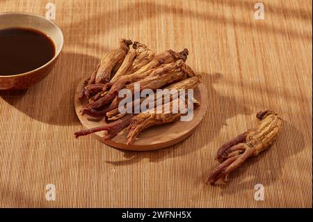 Roter Ginseng auf Holzschale mit einer Schüssel Medizin. Roter Ginseng (Panax Ginseng) hilft, die Immunfunktion des Körpers zu stärken, die Sym zu unterstützen Stockfoto