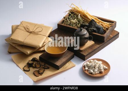 Ein Gericht mit Poria cocos, Szechuan Lovage Rhizome, eine Medizingeschüssel und ein irdener Topf auf einem Podium, ausgestellt mit einem Tablett mit einigen Kräutern. Pflanzliche medici Stockfoto