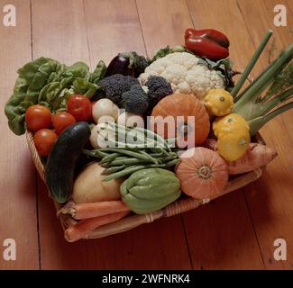 KORB AUF HÖLZERNER KÜCHENBANK MIT VERSCHIEDENEN FRISCH GEERNTETEN GEMÜSESORTEN. Stockfoto