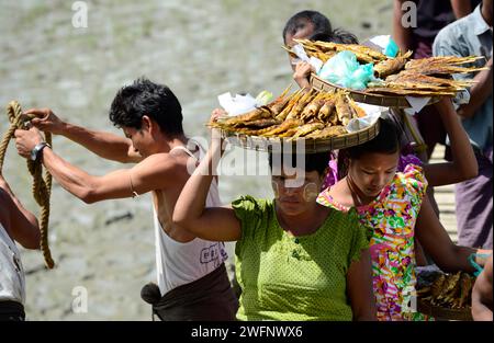 Arkanesische Frauen verkaufen gegrillten Fisch an einem kleinen Pier an einem kleinen Fluss in der Nähe von Mrauk-U im Staat Rakhine, Myanmar. Stockfoto