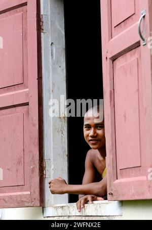 Junge buddhistische Mönche schauen aus dem Klosterfenster in Mrauk-U, Myanmar. Stockfoto