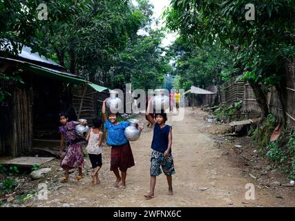 Junge arkanesische Mädchen, die Wasserkrüge in ihr Dorf in Mrauk-U im Staat Rakhine, Myanmar, tragen. Stockfoto