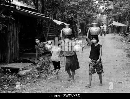 Junge arkanesische Mädchen, die Wasserkrüge in ihr Dorf in Mrauk-U im Staat Rakhine, Myanmar, tragen. Stockfoto