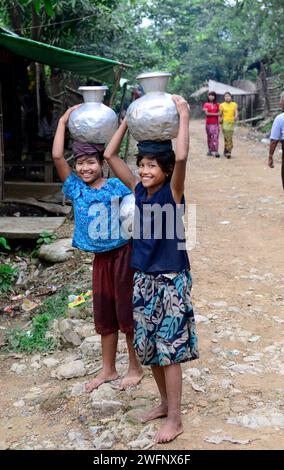 Junge arkanesische Mädchen, die Wasserkrüge in ihr Dorf in Mrauk-U im Staat Rakhine, Myanmar, tragen. Stockfoto