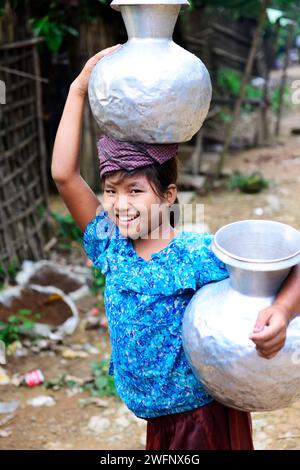 Junge arkanesische Mädchen, die Wasserkrüge in ihr Dorf in Mrauk-U im Staat Rakhine, Myanmar, tragen. Stockfoto