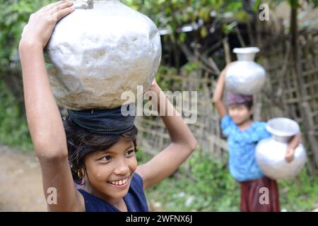 Junge arkanesische Mädchen, die Wasserkrüge in ihr Dorf in Mrauk-U im Staat Rakhine, Myanmar, tragen. Stockfoto