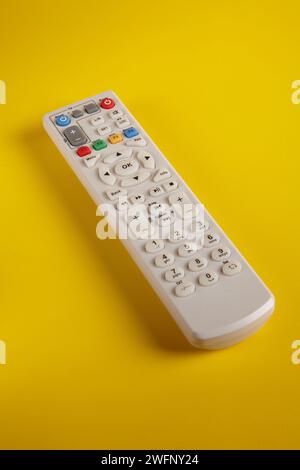 Eine Fernbedienung der TV-Box mit verschiedenen Funktionstasten auf gelbem Hintergrund Stockfoto