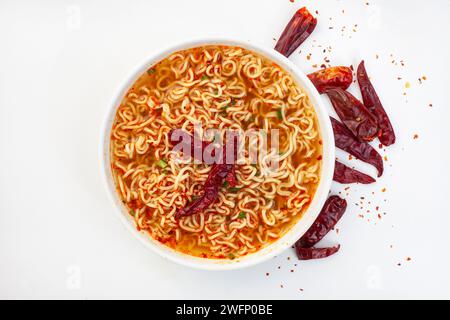 Scharfe Instant Nudeln oder Ramen mit getrocknetem Chili auf weißem Hintergrund mit Kopierraum. Flache Lage, Draufsicht. Stockfoto