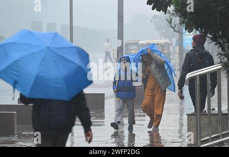 Neu-Delhi, Indien. Januar 31, 2024. NEW DELHI, INDIEN - JANUAR 31: Pendler schützen sich am 31. Januar 2024 vor plötzlichem Regen im Mandi House in New Delhi, Indien. (Foto: Arvind Yadav/Hindustan Times/SIPA USA) Credit: SIPA USA/Alamy Live News Stockfoto