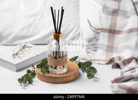 Aromatischer Lufterfrischer aus Schilf, Eukalyptusblätter und Kerze im Schlafzimmer Stockfoto