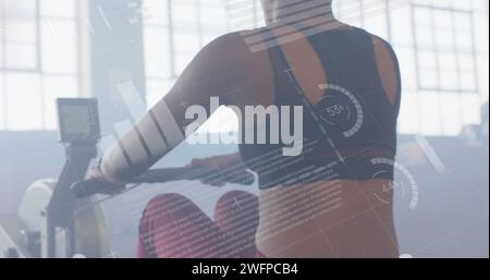 Bild der Datenverarbeitung auf der Schnittstelle über das Training von birassischen Frauen am Rudergerät im Fitnessstudio Stockfoto