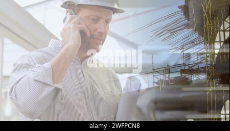 Bild eines männlichen kaukasischen Architekten mit Telefon und Plänen über dem Stadtbild Stockfoto