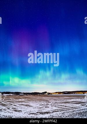 Eine atemberaubende Darstellung der aurora Borealis, die den Himmel und ein malerisches Feld beleuchtet Stockfoto