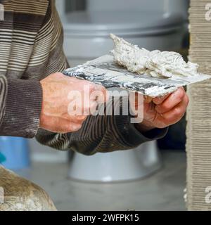 Zement oder Putz auf einem Spachtel. Spachtel in den Händen eines Arbeiters Stockfoto
