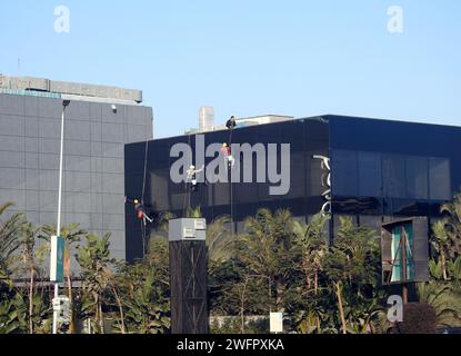 Kairo, Ägypten, 23. Januar 2024: Wartung und Reinigung des Außenbereichs eines Gebäudes, Glasreinigung durch Arbeiter an Drähten, um Reinigungsservice durch zu erbringen Stockfoto