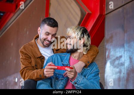 Junge schwule Paare, die sich liebevoll mit einer Geschenkbox anschauen. Liebende Stockfoto