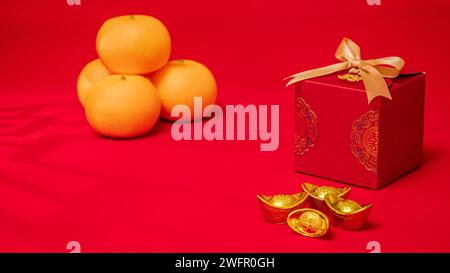 Chinesischer roter Hintergrund für das Mondneujahr. Antike chinesische Barren aus Barren, orange, rote Geschenkbox mit goldener Schleife zum chinesischen Neujahrsfest Stockfoto