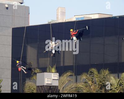 Kairo, Ägypten, 23. Januar 2024: Wartung und Reinigung des Außenbereichs eines Gebäudes, Glasreinigung durch Arbeiter an Drähten, um Reinigungsservice durch zu erbringen Stockfoto