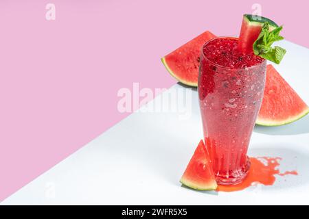 Erfrischendes kaltes Sommergetränk Wassermelone Slushie, eisgekühltes Granita-Dessertgetränk, zerkleinertes Wassermelonen-Eis auf trendigem, weiß-rosa Hintergrund Stockfoto