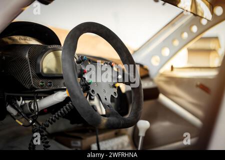 Innenraum des Rennwagens, Cockpit bei warmem Sonnenuntergang. Armaturenbrett und Veloursleder-Lenkrad. Stockfoto