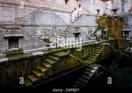 Drei Männer auf der Treppe im Treppenhaus Toorji Ka Jhalra in Jodhpur, Rajasthan, Indien Stockfoto